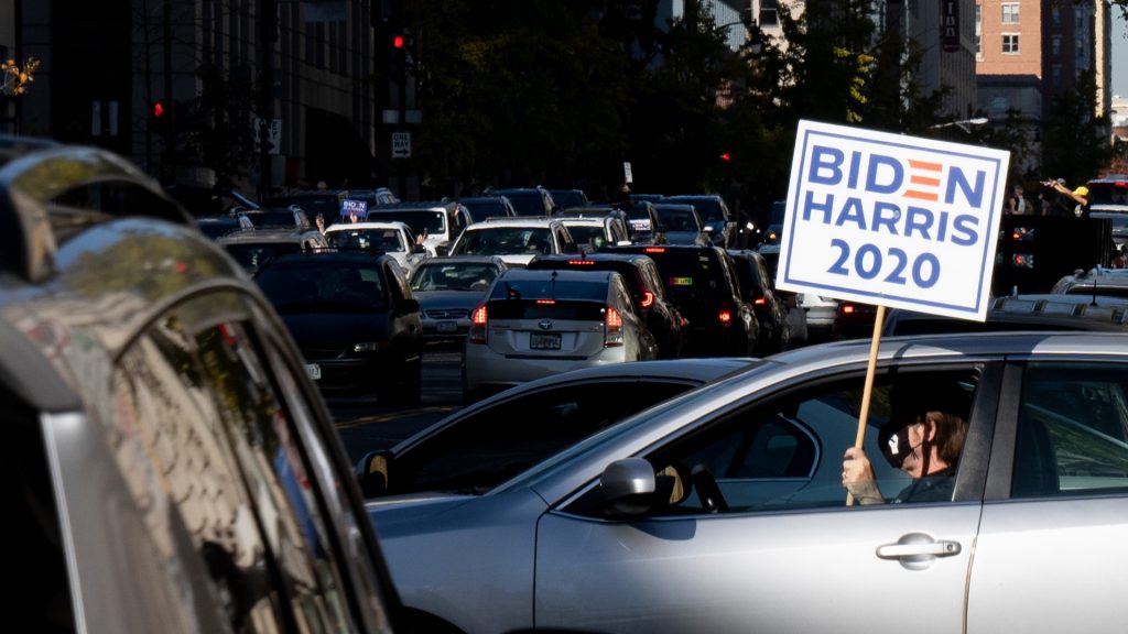 car driving with Biden-Harris sign.