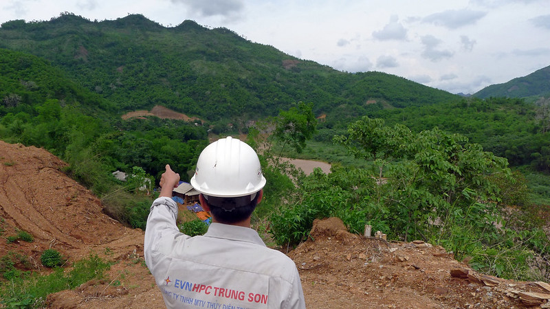 person in foreground pointing to forested area being cleared for construction