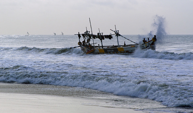 small fishing boat leaving the beach in wave