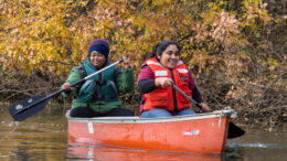 Two women paddle a canoe