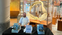 The author sitting in a museum behind a display of his books.