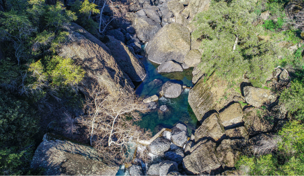 Aerial view of narrow creek with large boulders.