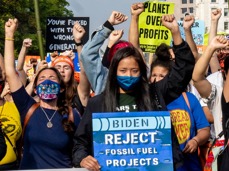 Women marching with signs to reject fossil fuel development