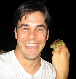 Headshot of man in white t-shirt with frog on his hand