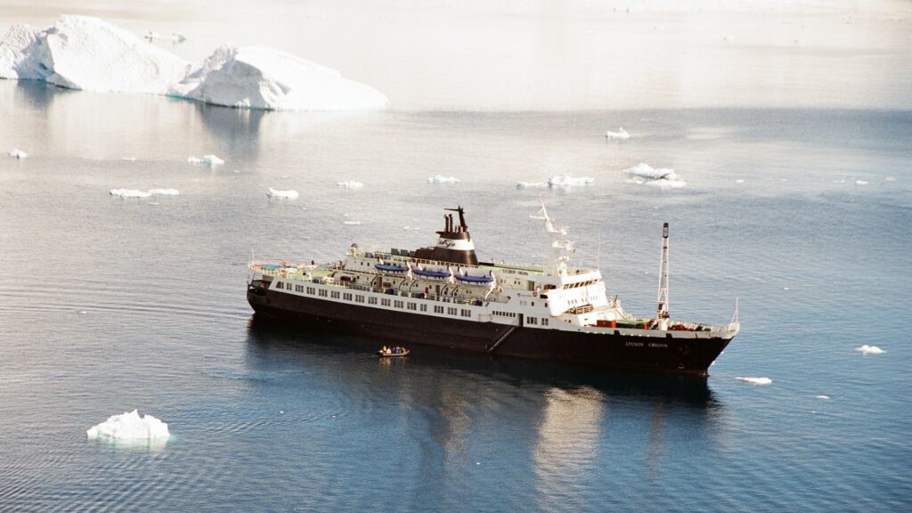 Large ship in ocean waters with two icebergs