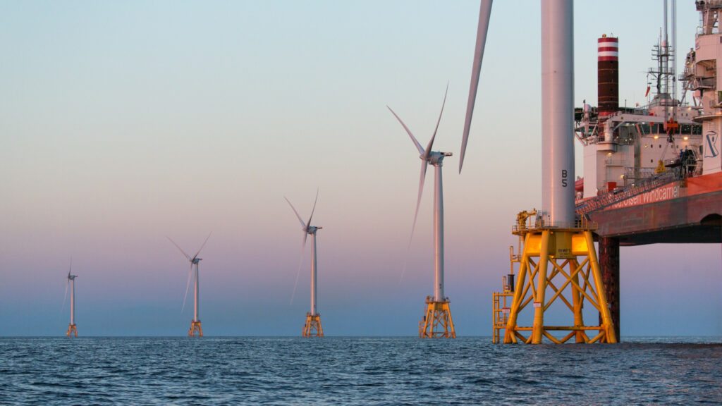 A row of wind turbines rise out of the ocean