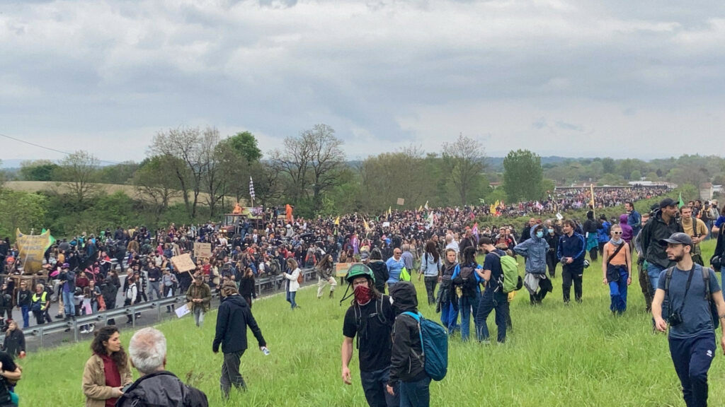 Hundreds of protestors gather along a street