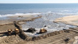 Bulldozers push sand at a beach