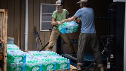 Students lift packs of water from into the back of a truck