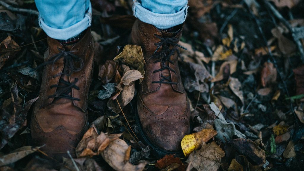 A pair of soiled boots on leaf-covered ground