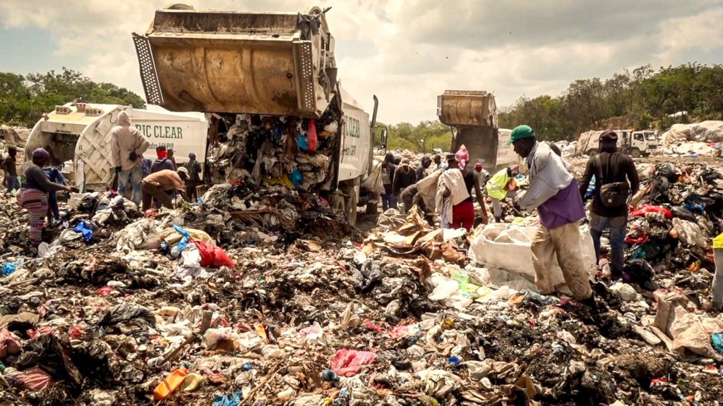People sort through garbage as more is dumped onto a landfill