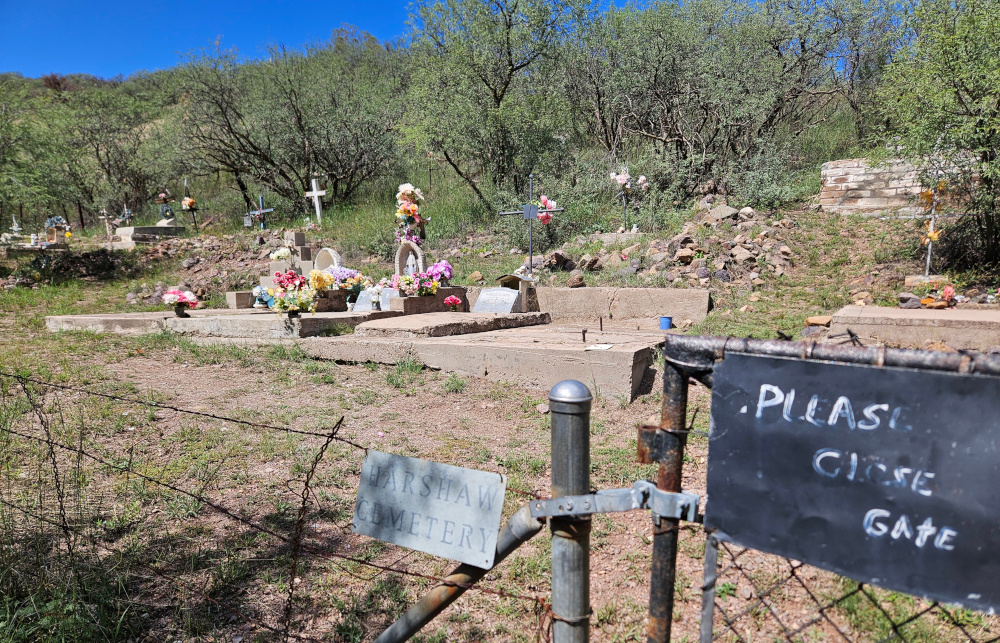 A small, unkempt, dusty cemetery surrounded by a wire fence