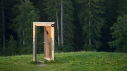 A doorway in a field with trees in the background